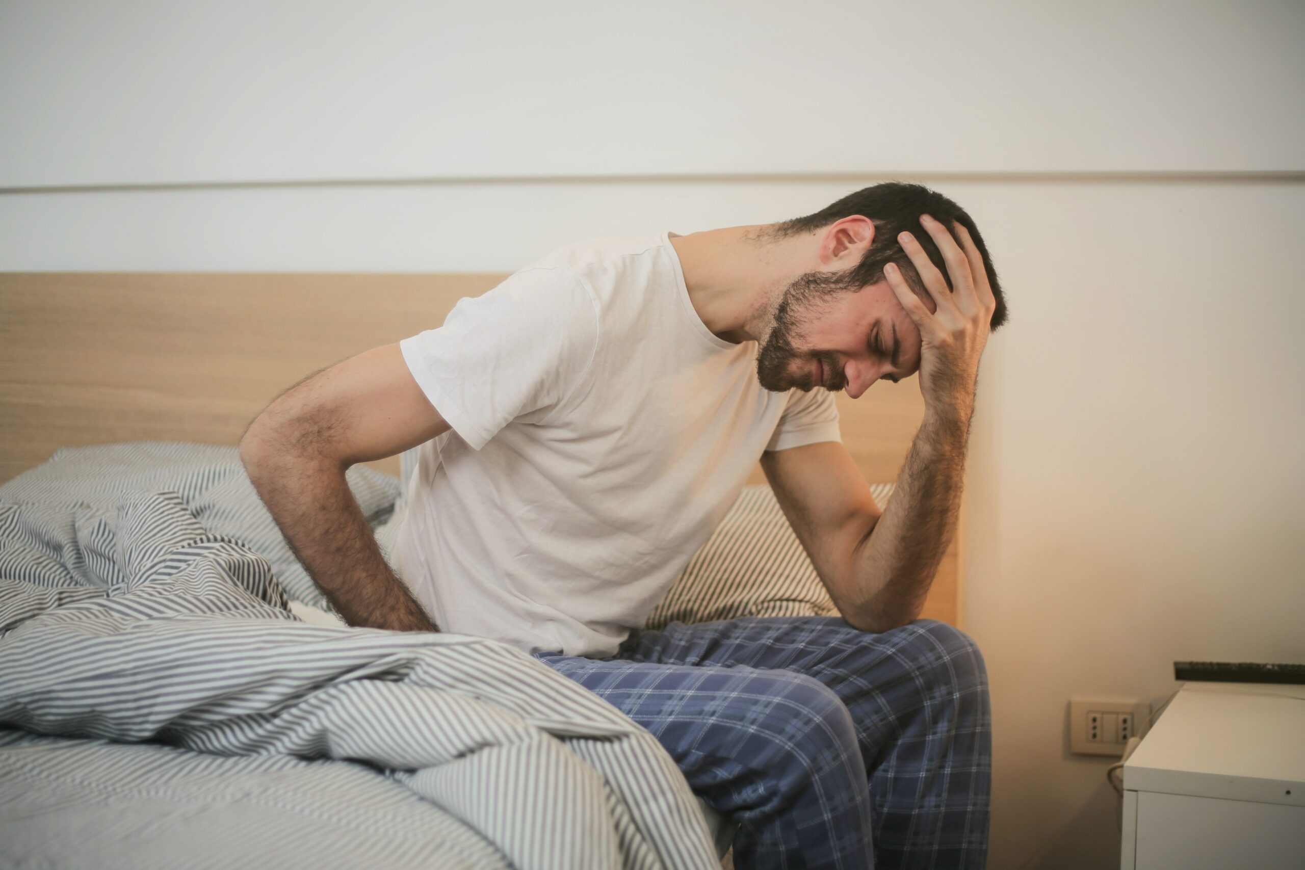 man in bed with headache and back pain