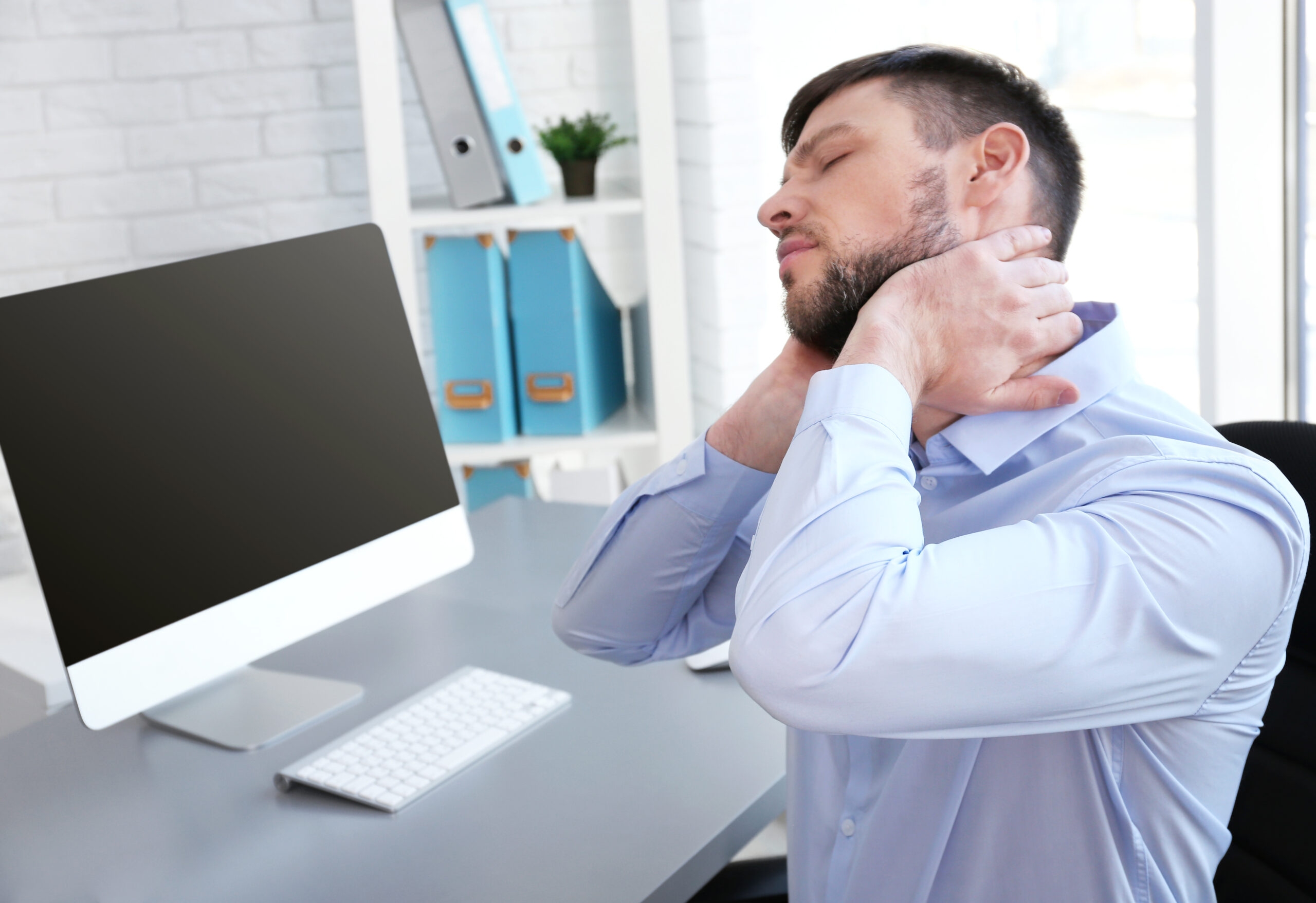 man with neck pain at a desk