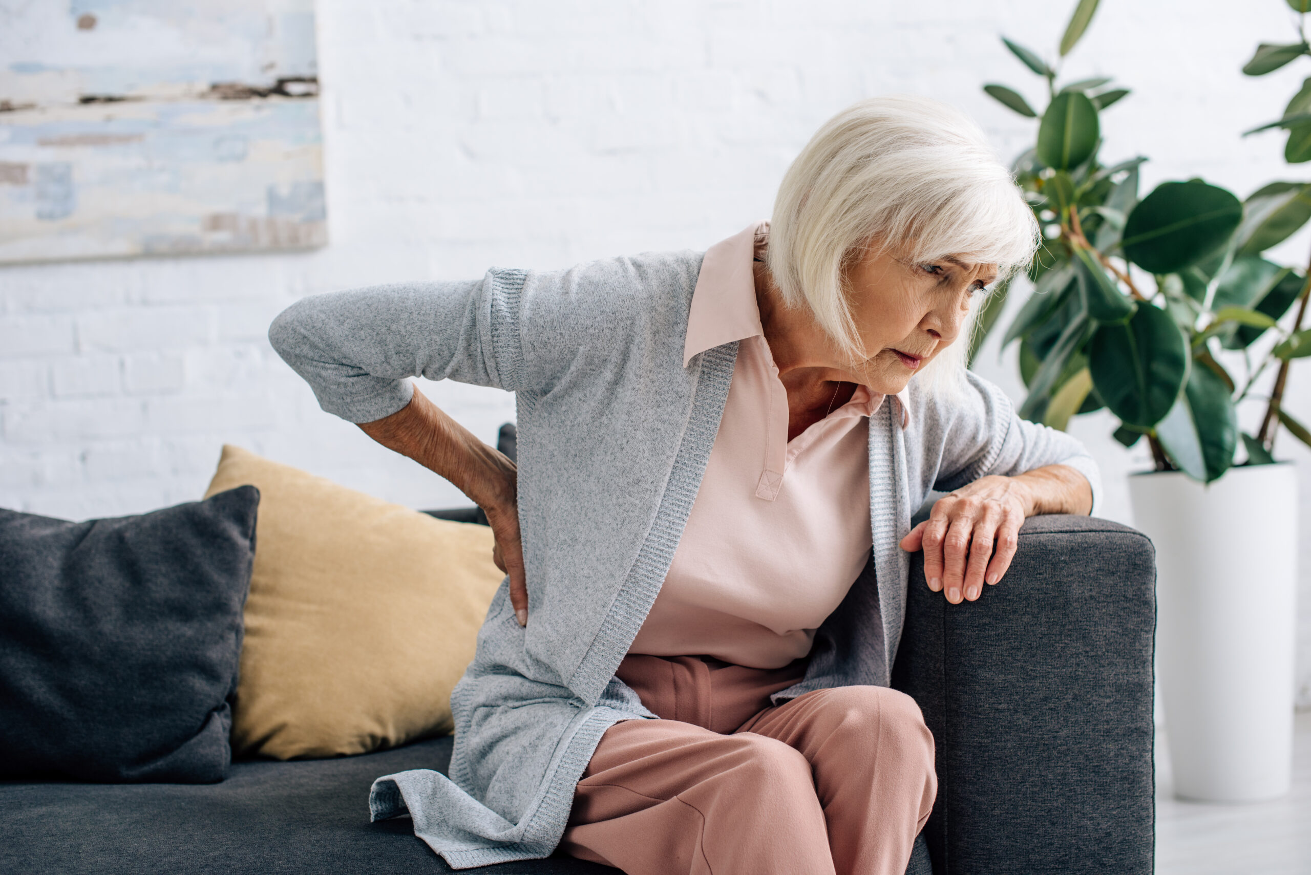 senior women with hip pain getting off the couch